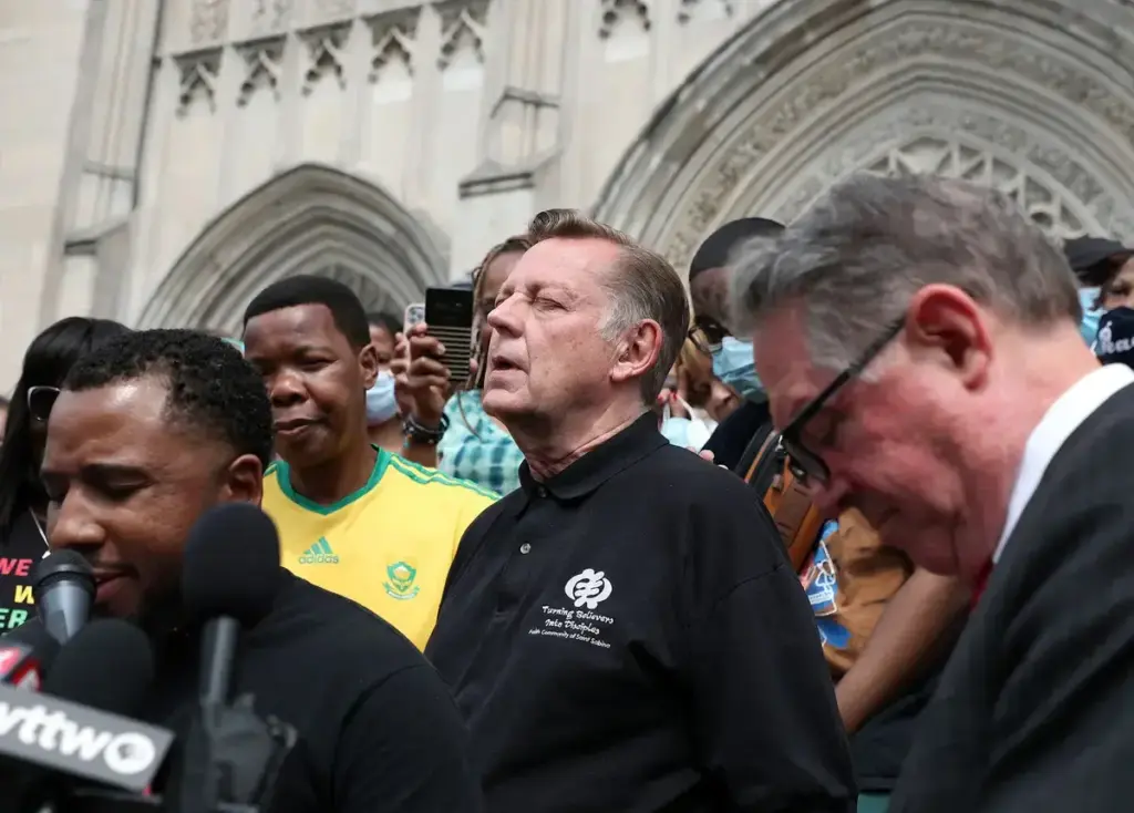 January 4, 2022: Surrounded by supporters, the Rev. Michael Pfleger, center, closes his eyes in prayer before speaking at a news conference outside St. Sabina Parish in Chicago, Illinois on May 24, 2021, after an independent review board determined t